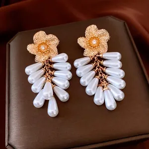 Vintage gold flower earrings with pearl tassels and zircon details on dark silk background