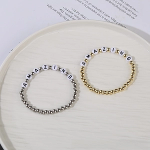 Close-up of gold and silver hematite beaded bracelets with AMAZING letter charms on white plate