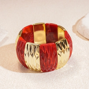 Detail of wide elastic bracelet with red marble resin and gold diamond pattern metal links
