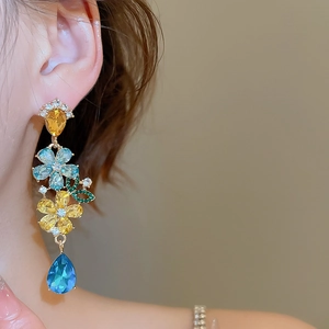 Close-up of long floral drop earrings with colorful zircon crystals on a female model