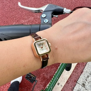 Vintage rose gold square quartz watch with brown leather strap worn outdoors