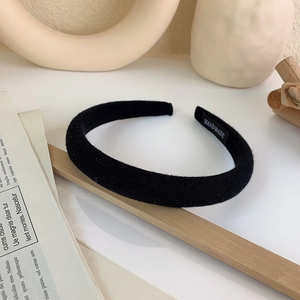 Close-up of black velvet padded headband featuring a white handmade woven label detail