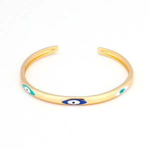 Bracciale a fascia dorato a C con motivi occhio del male in smalto blu su sfondo bianco