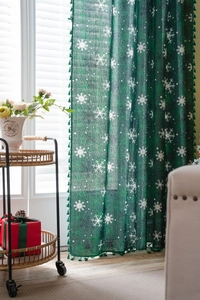 Detail of green Christmas curtain with white snowflake patterns and elegant fringe trim