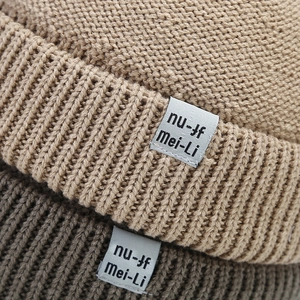 Detail view of knitted wool fabric texture on light coffee and dark grey beanies