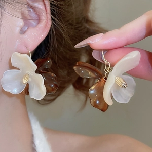 Detail of floral acrylic earrings with amber resin petals and elegant tassel hooks