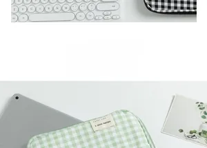Detailed view of green checkered laptop sleeve with Happy Life label on a desk
