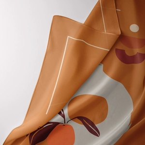 Close-up of orange silk scarf showing abstract geometric prints and smooth fabric folds