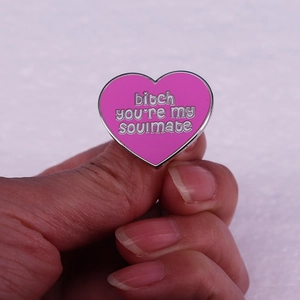 Pink heart enamel pin with bitch you're my soulmate text held in hand for close-up view