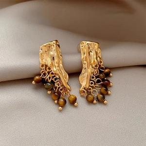 Vintage gold textured studs with tiger eye beaded tassels on a beige silk fabric