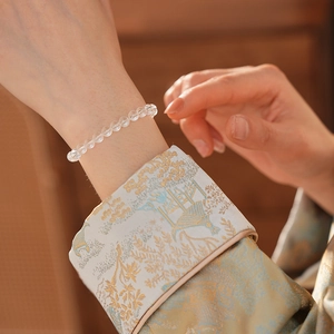 Detail of clear white crystal beaded bracelet worn with an embroidered cuff
