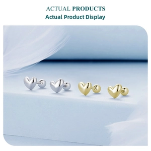 Detailed view of mini heart-shaped stud earrings in polished silver and gold finishes