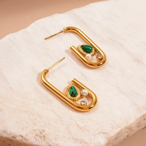 Detail of gold U-shaped earrings with green malachite teardrop, pearl, and rhinestone