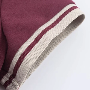 Détail de la manche bordeaux avec revers en tricot côtelé rayé beige et rouge