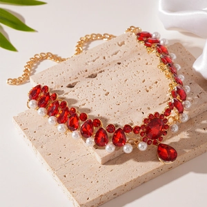 Close-up of luxury vintage necklace with red crystals and pearls on stone tray