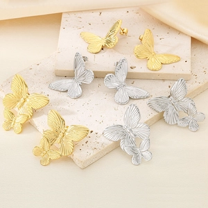 Detailed view of gold and silver butterfly earrings with vintage metal texture on silk