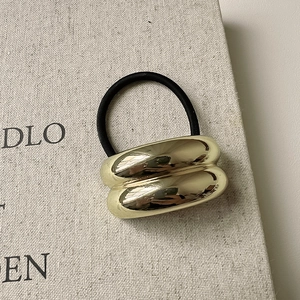 Detail of polished gold double-tube metal hair tie with high-elastic black rubber band