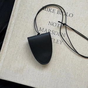 Detail of black pebbled leather magnetic glasses holder pendant on a textured book