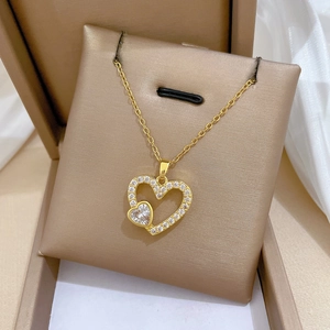 Détail d'un pendentif double cœur doré orné de strass brillants dans son coffret