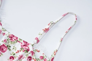 Detail of adjustable straps and lace trim on a white floral print summer camisole top