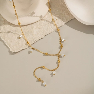 Dettaglio della collana in acciaio inossidabile dorato con piccole perle bianche
