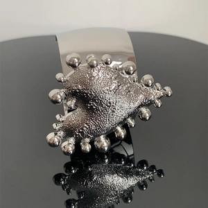 Macro detail of silver heart metal bracelet featuring a unique hammered textured heart design