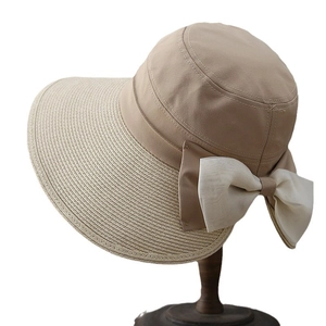 Straw patchwork sun hat for women with a large white bow on a wooden stand