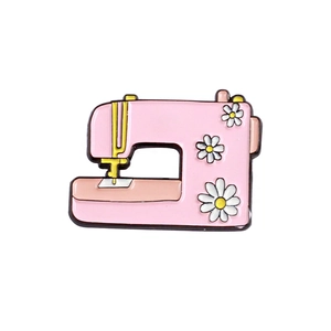 Vintage pink enamel sewing machine brooch with white daisy flower motifs and gold accents