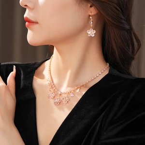 Close-up of pink flower jewelry set including necklace and earrings worn by model