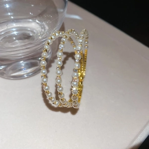 Detailed macro of gold pearl and rhinestone layered bracelet with shimmering light