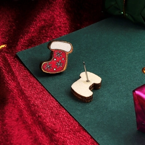 Close-up of festive red and white wooden Christmas stocking stud earrings on green card
