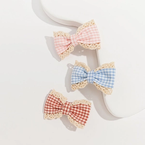 Detailed view of pink, blue, and red plaid fabric bows with delicate lace trimming