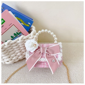 Close-up of pink tweed girls handbag with lace bow and elegant pearl handle detail