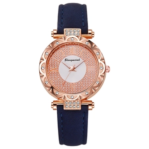 Detail of rose gold watch case with crystal bezel and dark blue leather strap