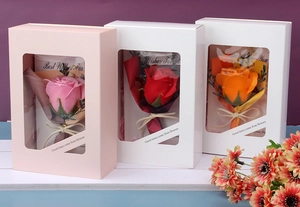 Three elegant soap flower gift boxes with transparent windows and ribbons on a shelf