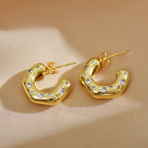 Detailed close-up of C-shaped gold hoop earrings with colorful zircon and pearls