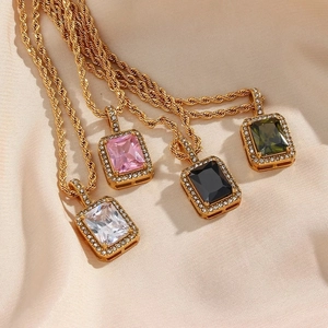 Detail of vintage twisted gold chains with colorful square zircon pendants on beige fabric