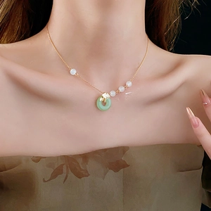 Detailed view of necklace with green peace buckle and gold ginkgo leaf on model