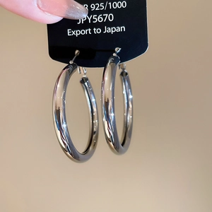 Close-up of polished S925 sterling silver hoop earrings on a display card