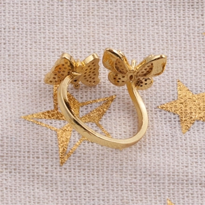 Macro shot of gold-plated double butterfly ring on beige fabric with stars