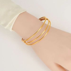 Three adjustable 18K gold-plated stainless steel bangles worn on a woman's wrist