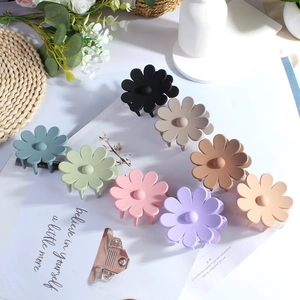 Set of 8 matte flower hair claws in assorted pastel colors on a fashion magazine