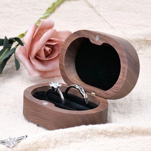 Black walnut wood double ring storage box with two silver wedding bands on beige linen
