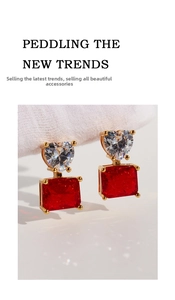 Macro view of gold earrings with clear heart zircon and red rectangular gemstone
