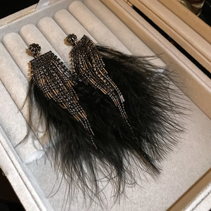 Detail of dark gothic fringe earrings with black rhinestones and feathers on velvet