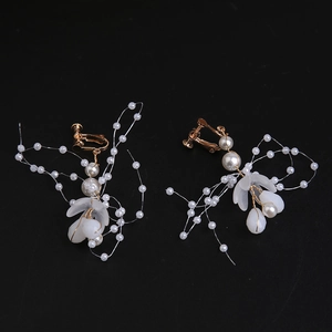 Close-up of handmade bridal ear clips with pearls and translucent flower petals