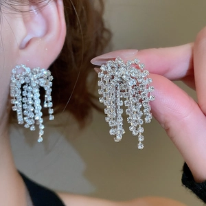 Detail of silver tassel earrings with multiple rows of rhinestones on a female model