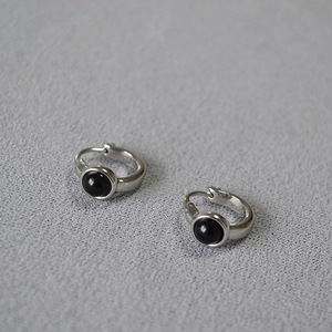 Macro shot of silver-plated brass hoop earrings with black agate stone inlay detail