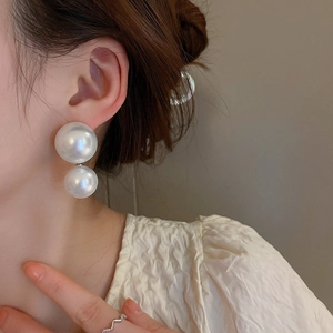 Minimalist double pearl drop earrings featuring vertical geometric design on model