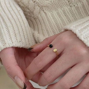 Close-up of minimalist gold open ring with black onyx bead on cozy knit background